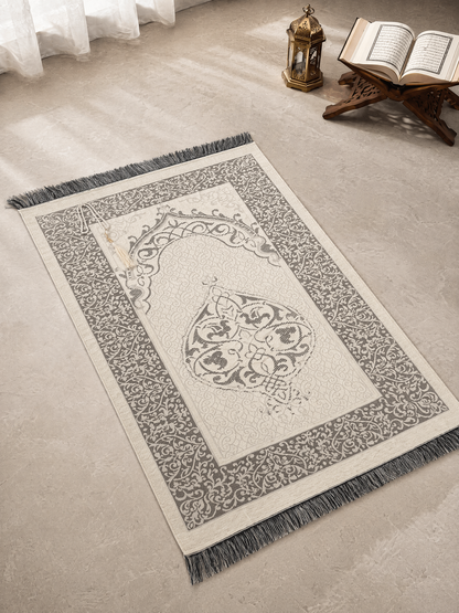 Cream white Ayahly prayer mat with woven arch design laid out beside a lantern and Quran stand